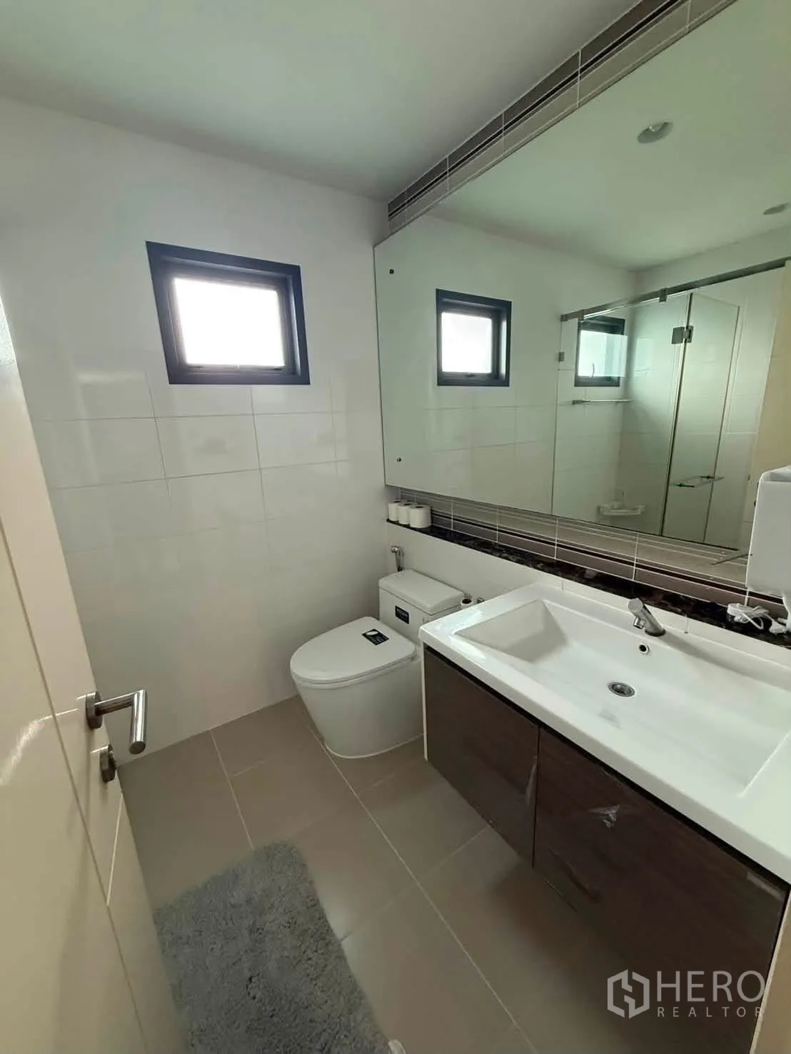 独栋房屋 for rent in Bang Kapi, Bangkok - 浴室有大镜面、洗手台柜与坐便器。