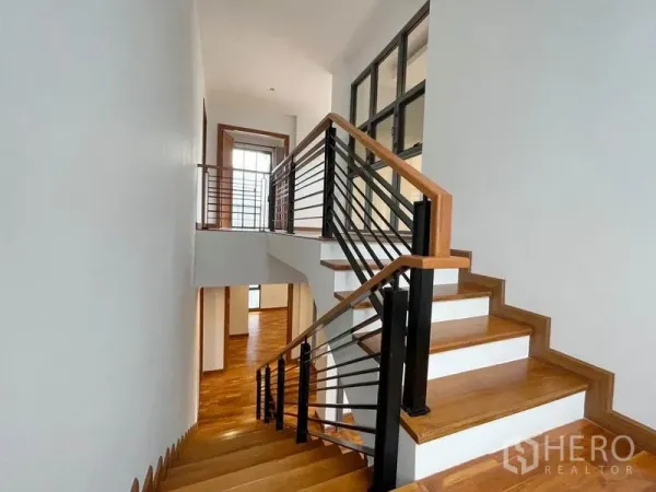 Detached House for rent in Bang Na, Bangkok - Wood staircase with metal railing connecting bright upper floors.