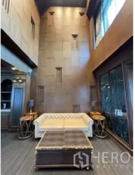 พื้นที่ขายปลีก ให้เช่า - มุมนั่งเล่นด้วยโซฟาหนังสไตล์คลาสสิก ผนังตกแต่งสูง พร้อมไฟวอลล์สกอนซ์และประตูกระจกบานใหญ่