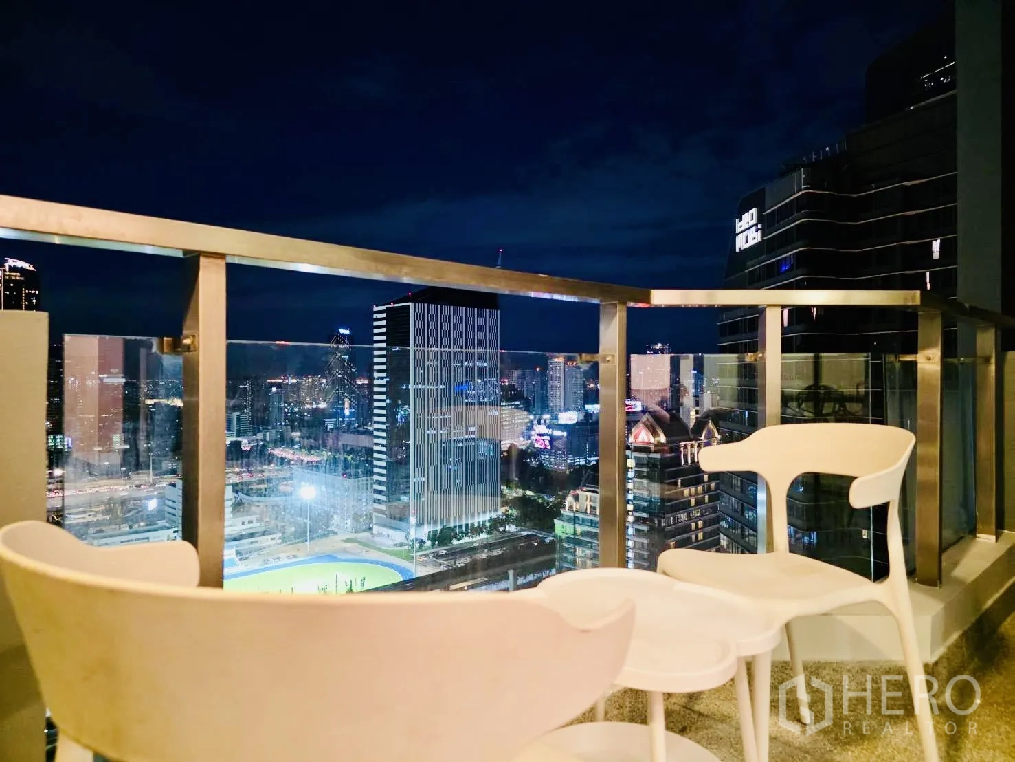 Condominium for rent in Huai Khwang, Bangkok - Balcony seating at night with panoramic skyline and high-rise towers.