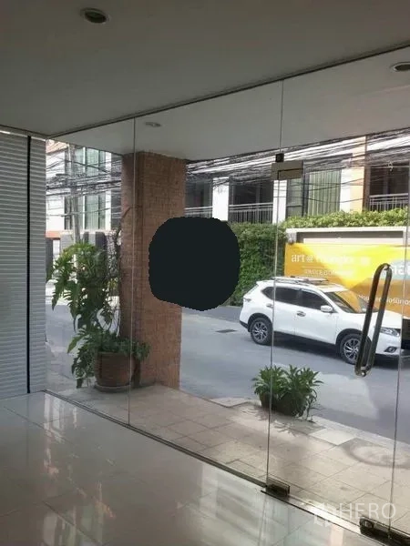 Home Office for rent in Watthana, Bangkok - Entrance lobby looking onto the lane through clear glass doors and plants.