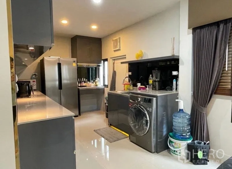 Detached House for rent - Functional kitchen with gray cabinetry, large refrigerator, washer, and ample counter space.