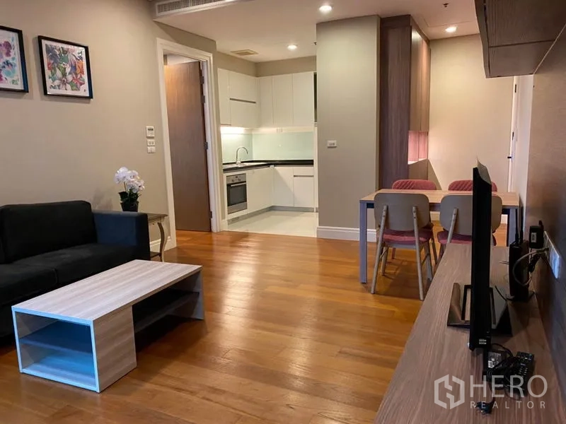 Condominium for rent in Khlong Toei, Bangkok - Spacious lounge with TV console, dining set and connected kitchen.