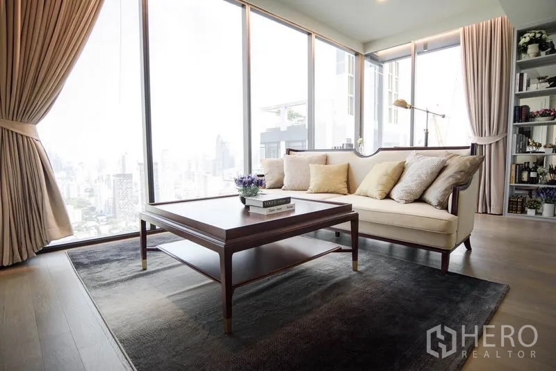 Condominium for rent or sale in Watthana, Bangkok - Bright living room with floor-to-ceiling windows, beige sofa, wood coffee table and city skyline view.