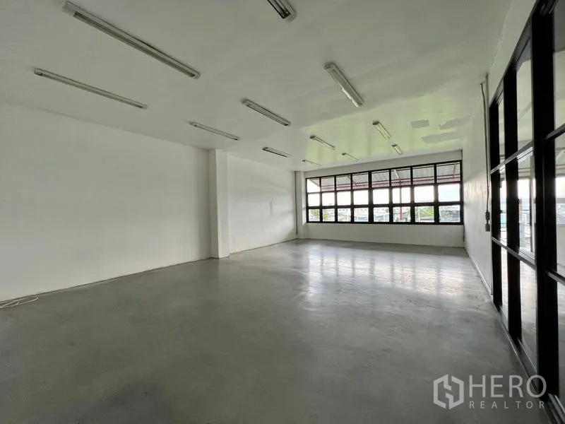 Warehouse for rent in Min Buri, Bangkok - Bright upper‑level room with wide windows and smooth concrete flooring.