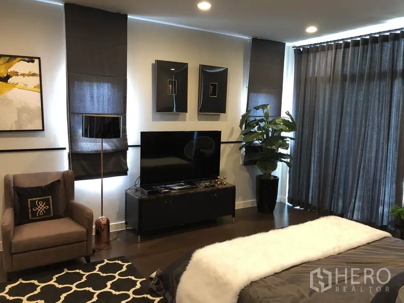 Detached House for rent in Bang Kapi, Bangkok - Spacious master bedroom with TV console, armchair and wide windows with blackout curtains.