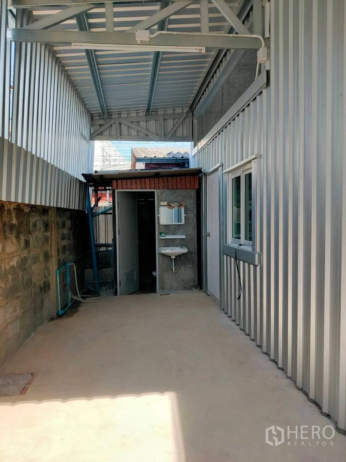 โกดัง for rent in Lat Phrao, Bangkok - ทางเดินด้านข้างมีหลังคา พร้อมประตูห้องน้ำและอ่างล้างมือ ผนังเมทัลชีท