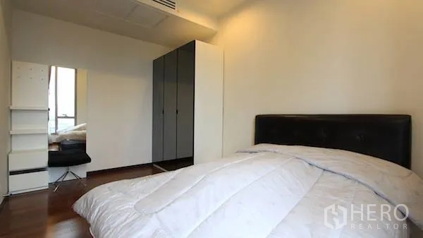Condominium for rent in Khlong Toei, Bangkok - Bedroom angle showing large wardrobe, dressing corner and warm wood flooring.