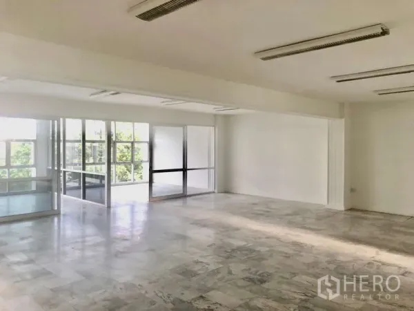 Office Space for rent in Bang Kapi, Bangkok - Bright open-plan office with marble-look flooring, white walls and glass partitions overlooking greenery.