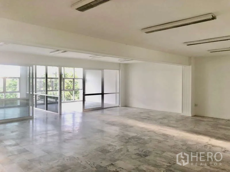 Office Space for rent in Bang Kapi, Bangkok - Bright open-plan office with marble-look flooring, white walls and glass partitions overlooking greenery.