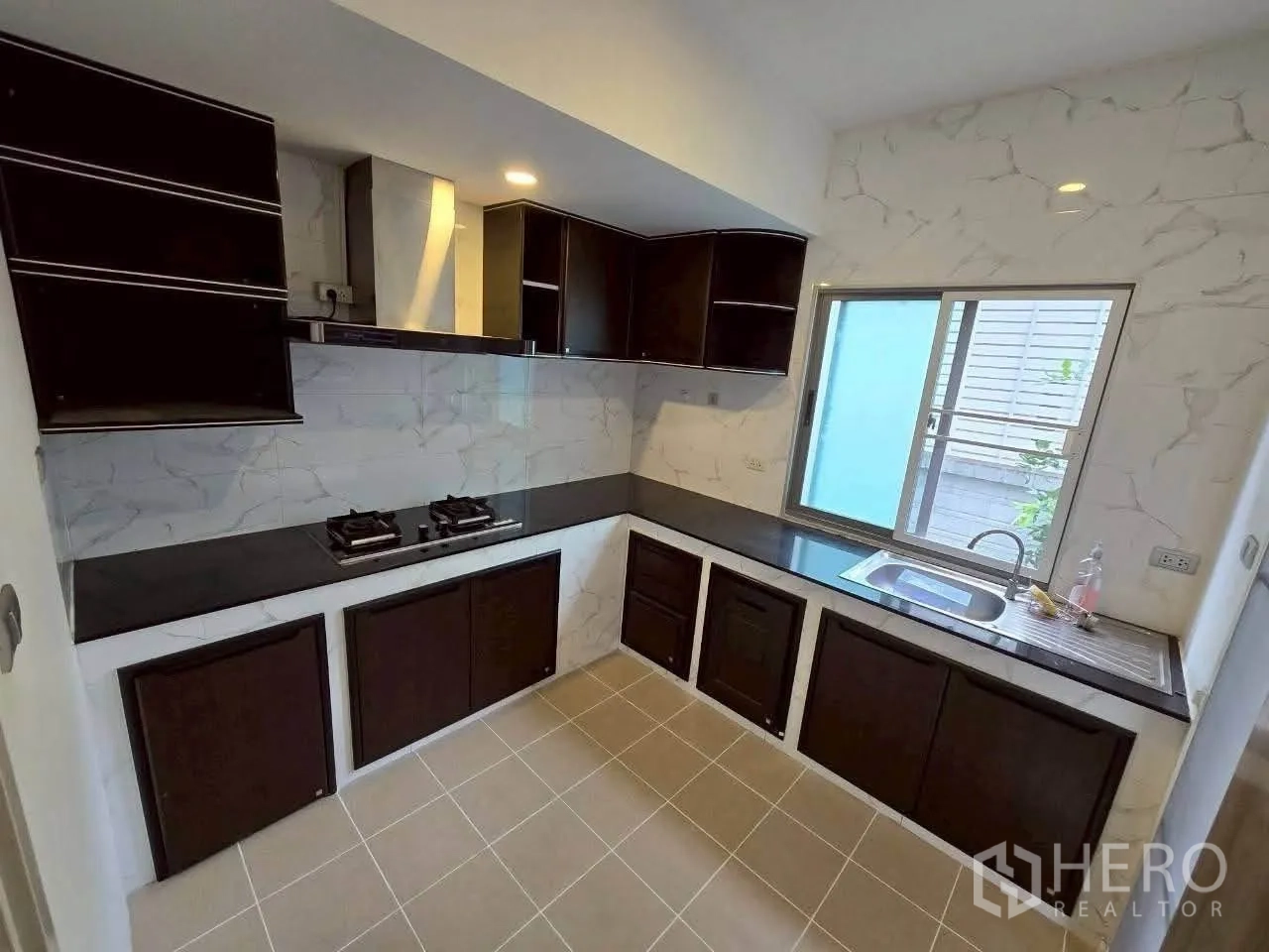 Detached House for rent or sale in Lat Krabang, Bangkok - Separate kitchen with dark cabinetry, gas hobs, hood, and windowed sink.