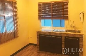 办公空间 出租在Bang Rak, Bangkok - 办公室茶水间，带水槽与木质台面，黄色墙面与百叶窗。