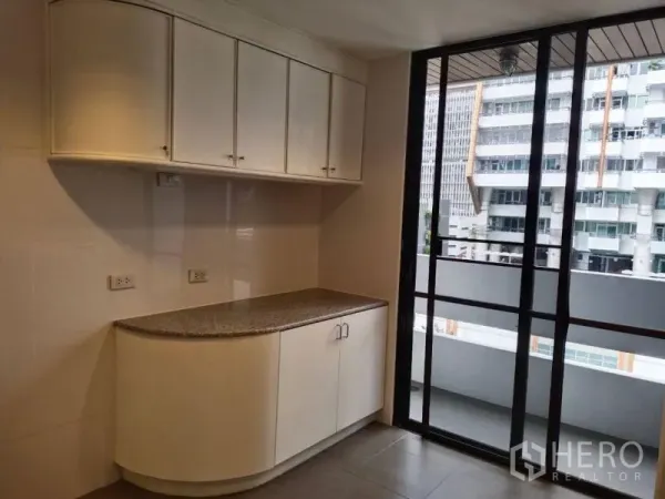 公寓 出租在Sathon, Bangkok - 带白色吊柜的小型备餐区，推拉玻璃门通向阳台。