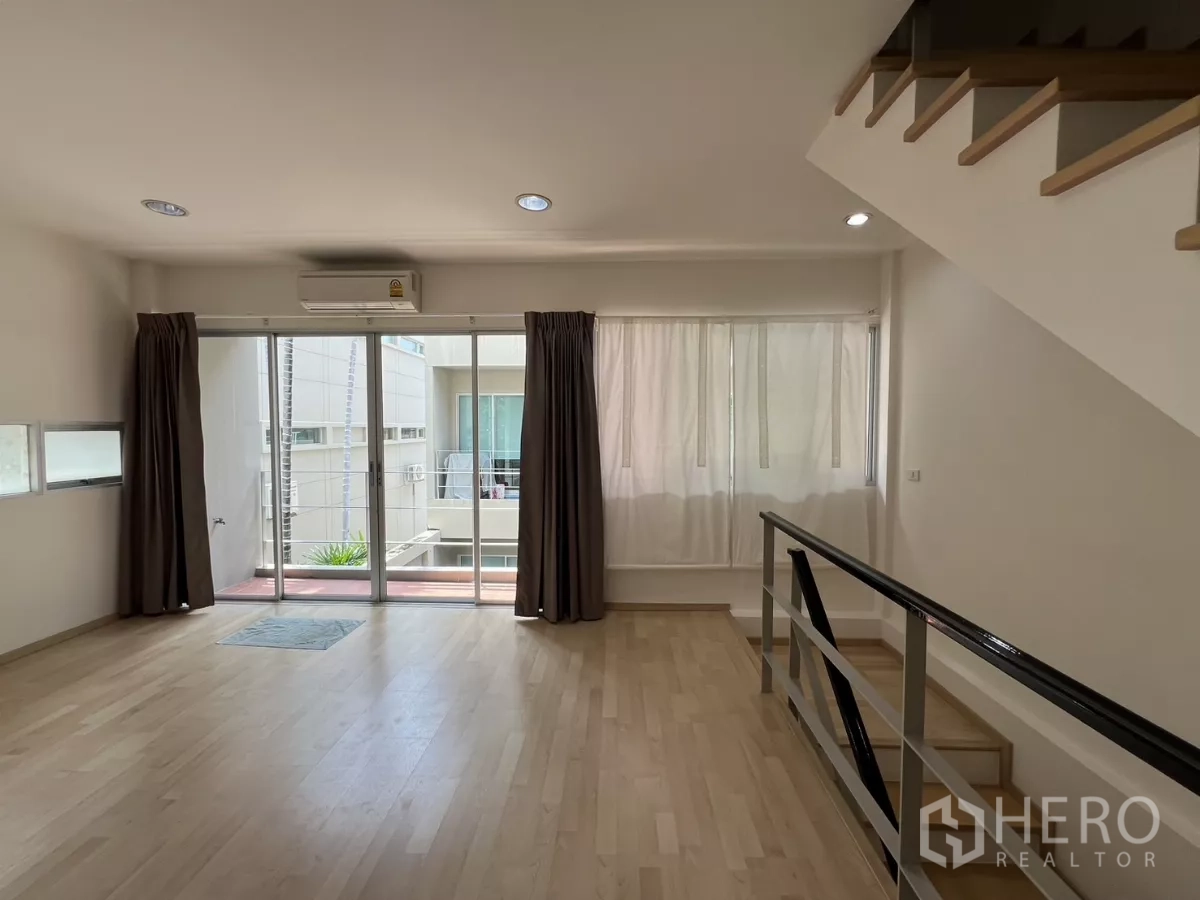Townhouse for rent in Suan Luang, Bangkok - Spacious landing lounge with stairs and sliding doors to a balcony.