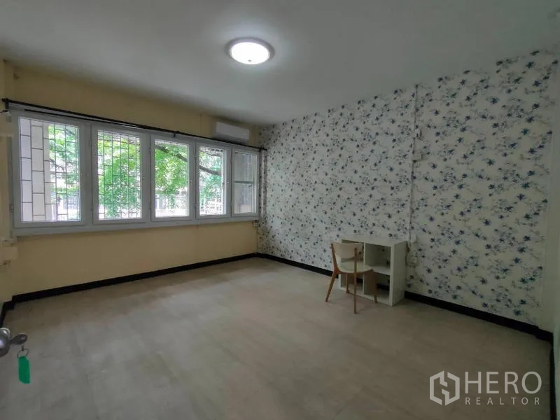 店屋 出租或出售在Bang Rak, Bangkok - 明亮卧室，花卉背景墙，大窗带防护栏，并设小书桌。