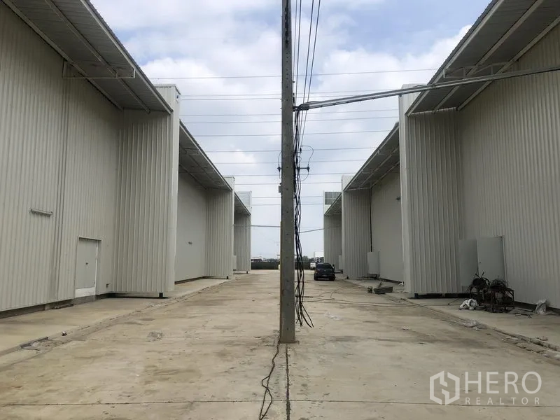 工厂 出租在Khlong Luang, Pathum Thani - 两排厂房之间的宽阔通道，设有电线杆与停车位。