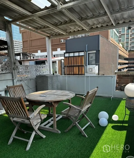 Townhouse for rent in Sathon, Bangkok - Rooftop terrace with green turf, round table, and city backdrop.