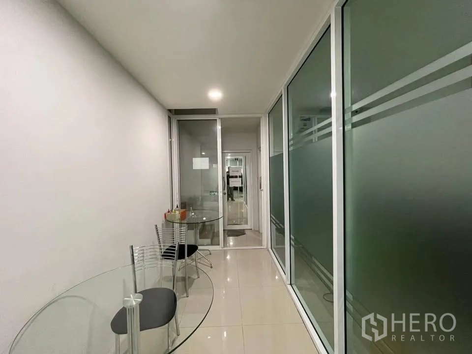 店屋 for sale in Prawet, Bangkok - 走道一侧设圆形玻璃桌与椅子，邻近玻璃隔断。