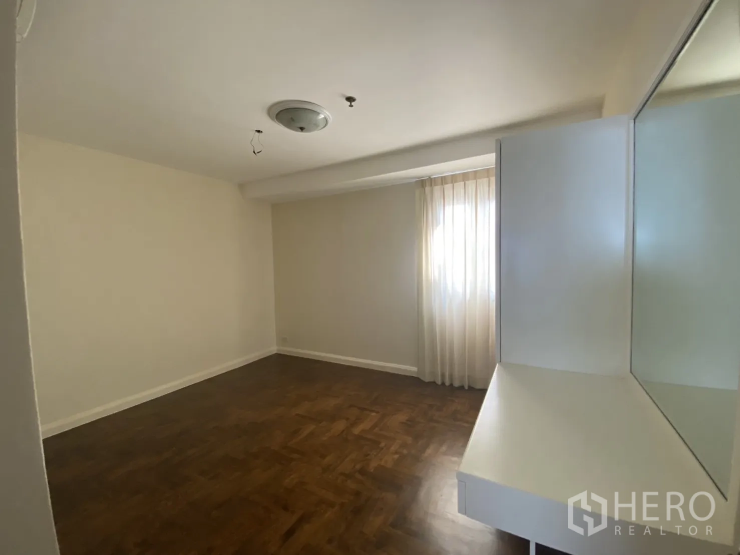 คอนโด ให้เช่าในWatthana, Bangkok - ห้องนอนพื้นไม้ หน้าต่างพร้อมผ้าม่านโปร่งและโต๊ะเครื่องแป้งมุมห้อง