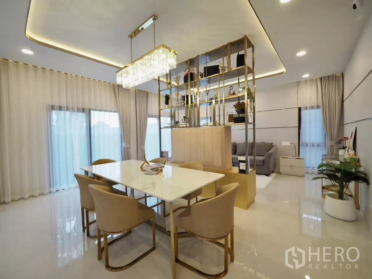 Detached House for rent in Bang Phli, Samut Prakan - Dining area with crystal chandelier and gold shelving divider beside sliding glass doors.