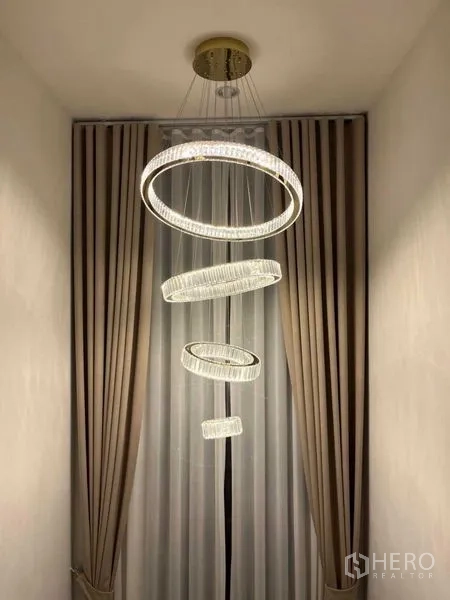 Detached House for rent or sale in Samut Prakan - Modern ring chandelier hanging in a stairwell with tall curtains.