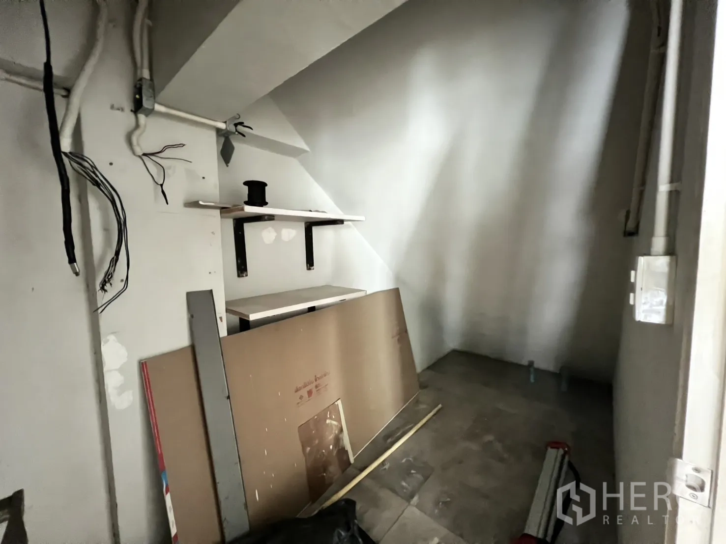 店屋 出租在Bang Rak, Bangkok - 楼梯下方的小型储物区，设置层架与裸露线路。