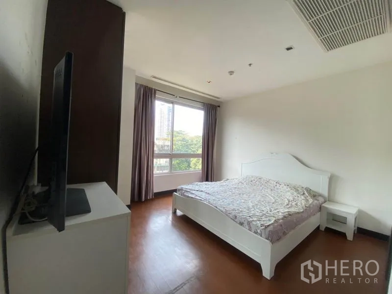 Condominium for rent in Yan Nawa, Bangkok - Primary bedroom with white bed, large window and leafy city outlook.