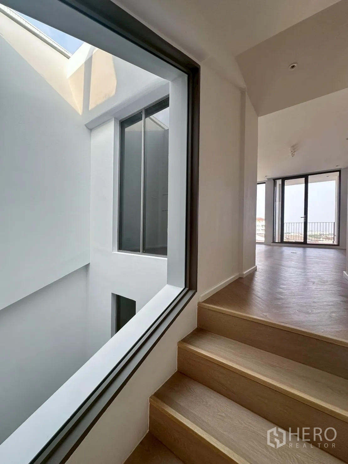 家庭办公室 for rent or sale in Watthana, Bangkok - 采光井旁的过道，通向带阳台门的明亮房间。