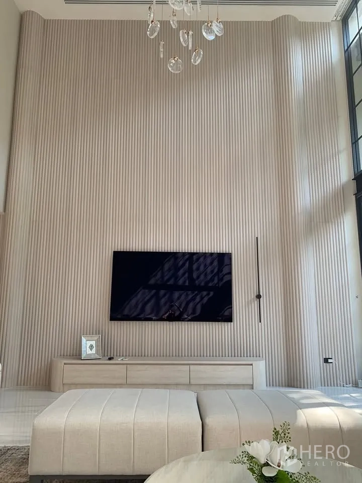 Townhouse for rent or sale in Watthana, Bangkok - Feature wall with mounted TV, media console, and pendant lighting.