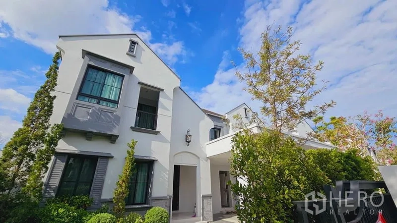 Detached House for rent or sale in Saphan Sung, Bangkok - Contemporary two-storey detached house exterior with trees and blue sky.