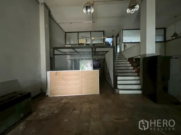 店屋 出租在Phra Khanong, Bangkok - 一层室内，高挑空间带夹层、楼梯和工业吊灯。