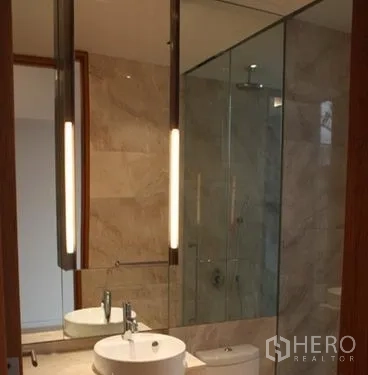 Condominium for sale in Sathon, Bangkok - Contemporary bathroom with glass-enclosed shower, vanity and tall mirror in the condo.