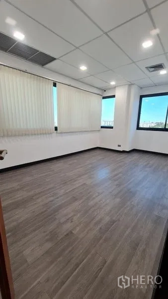 Office Space for rent in Watthana, Bangkok - Bright private office room with windows on two sides and wood-look flooring.