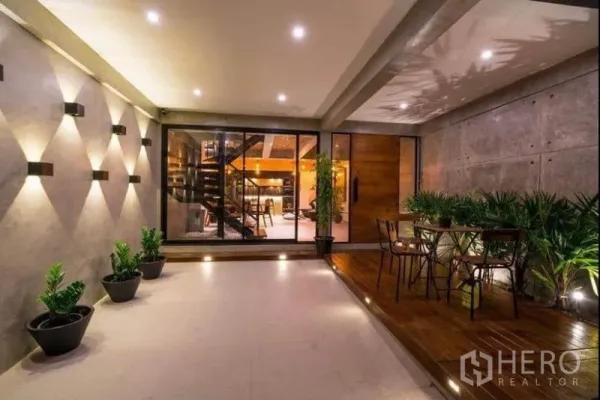 ทาวน์เฮาส์ ให้เช่าในKhlong Toei, Bangkok - ชานระเบียงมีหลังคาพร้อมไฟติดผนัง กระถางต้นไม้ และประตูบานเลื่อนเข้าสู่โถงรับแขก