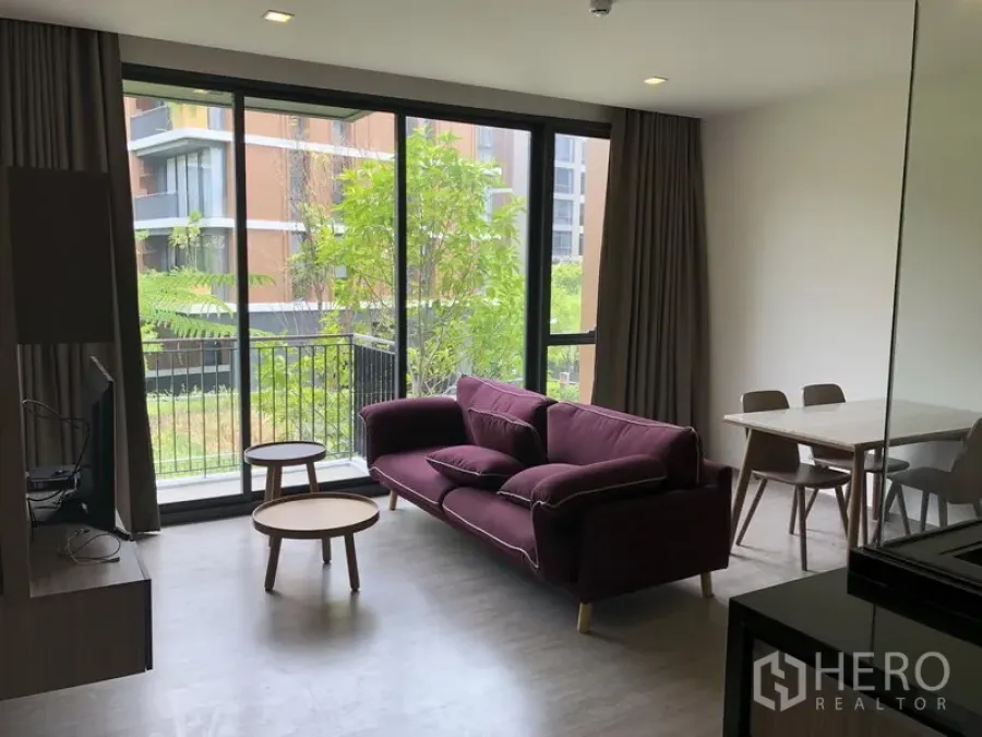 คอนโด ให้เช่าในWatthana, Bangkok - ห้องนั่งเล่นสว่างด้วยหน้าต่างสูงจรดเพดาน โซฟาสีม่วง ระเบียงวิวสวน พร้อมชุดโต๊ะกินข้าว