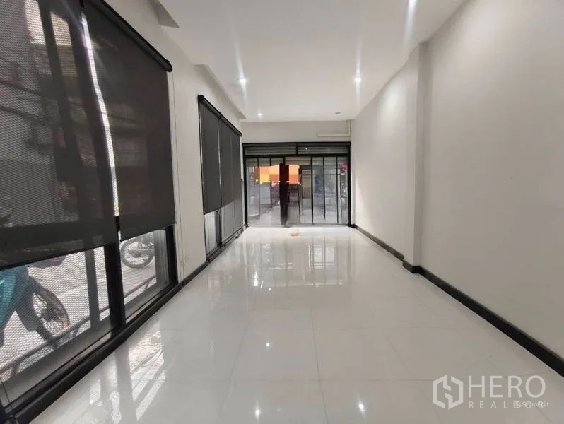 Shophouse for rent or sale in Pom Prap Sattru Phai, Bangkok - Long open-plan sales area with glass doors at both ends and recessed downlights.