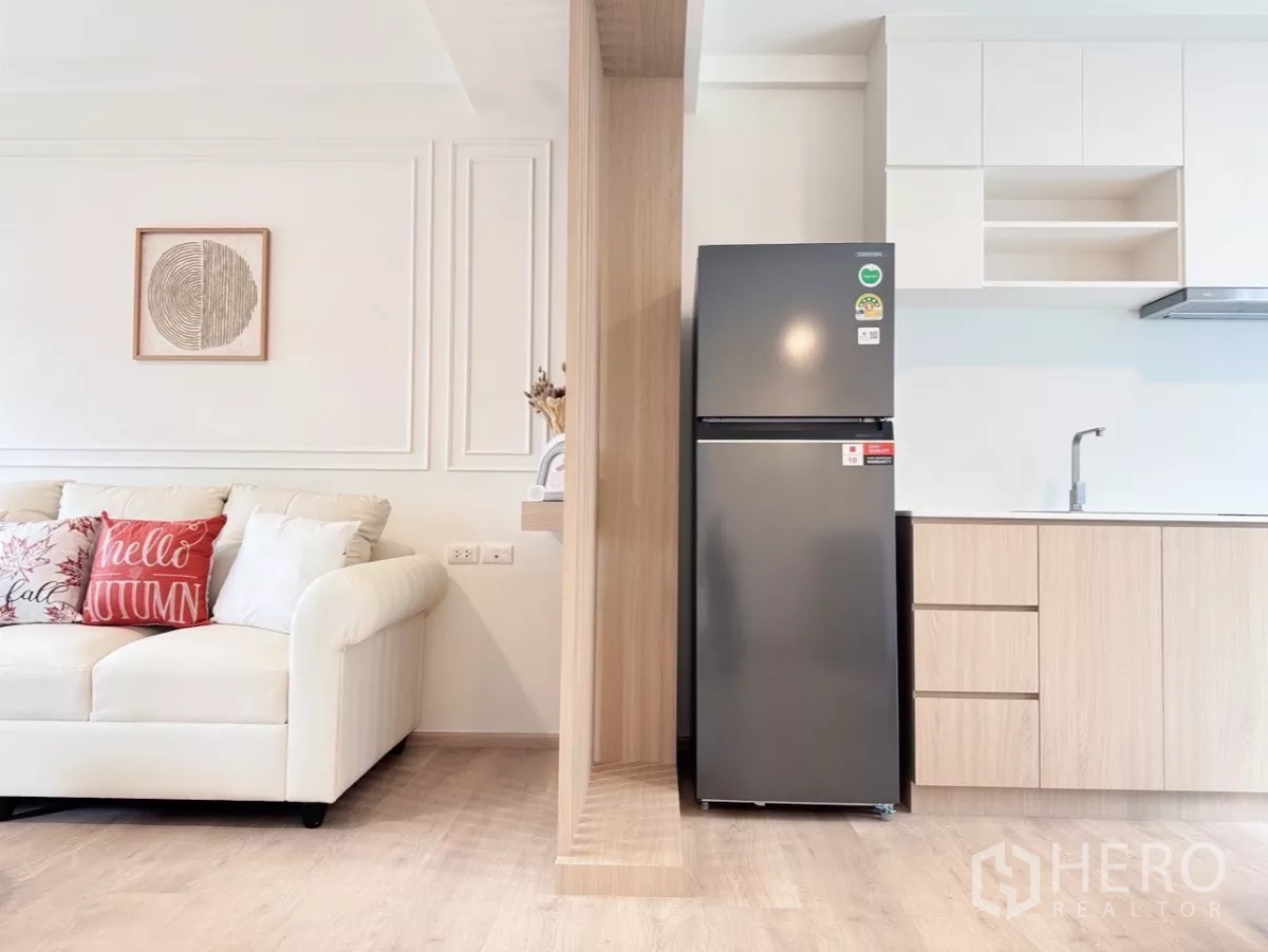 联排别墅 出租在Prawet, Bangkok - 木格栅隔断旁的冰箱与极简内置厨房。