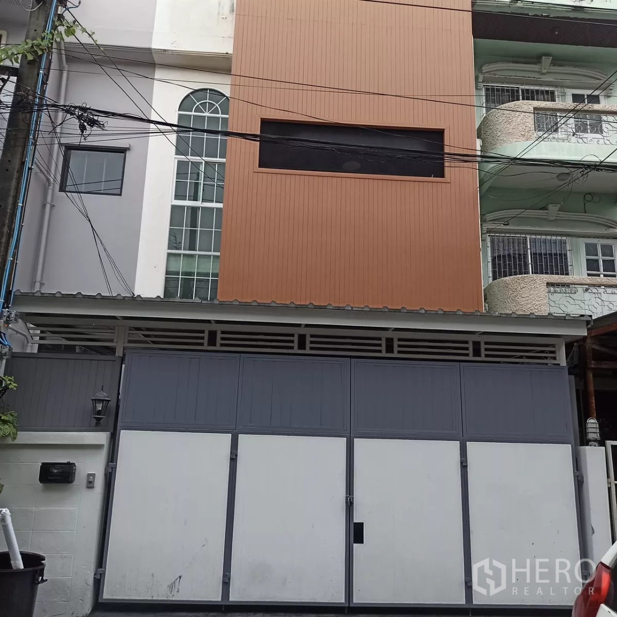 Townhouse for rent in Wang Thonglang, Bangkok - Three-storey townhouse exterior with tall gate and modern facade on a city lane.