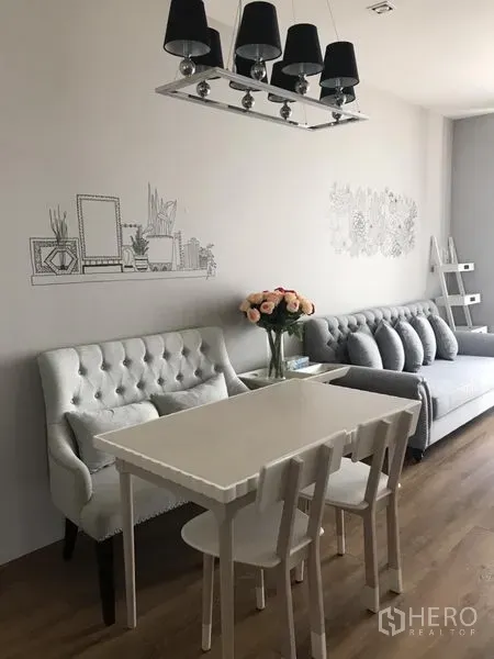 คอนโด ให้เช่าในKhlong Toei, Bangkok - มุมทานอาหารโต๊ะสีขาว ม้านั่งบุกำมะหยี่ โคมไฟระย้าสีดำ และงานวาดผนังข้างห้องนั่งเล่น