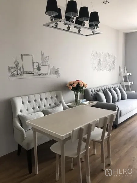 คอนโด ให้เช่าในKhlong Toei, Bangkok - มุมทานอาหารโต๊ะสีขาว ม้านั่งบุกำมะหยี่ โคมไฟระย้าสีดำ และงานวาดผนังข้างห้องนั่งเล่น