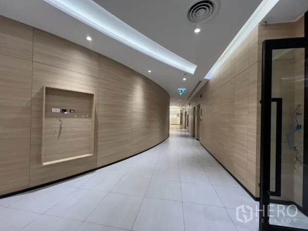 办公空间 出租在Huai Khwang, Bangkok - 简洁走廊，浅木饰面墙、嵌入式顶灯与大块地砖。