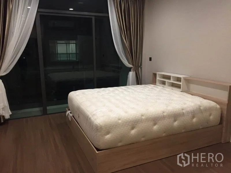 Detached House for rent in Bang Kapi, Bangkok - Master bedroom with large bed, floor-to-ceiling curtains and sliding glass doors to the balcony.