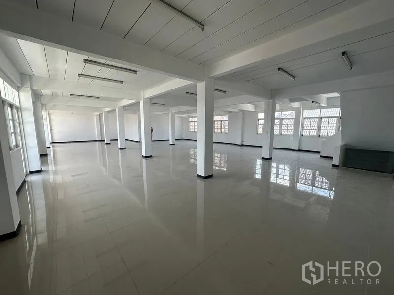 Home Office for rent in Phra Khanong, Bangkok - Expansive open-plan office floor with white columns, glossy tiles and fluorescent lighting.