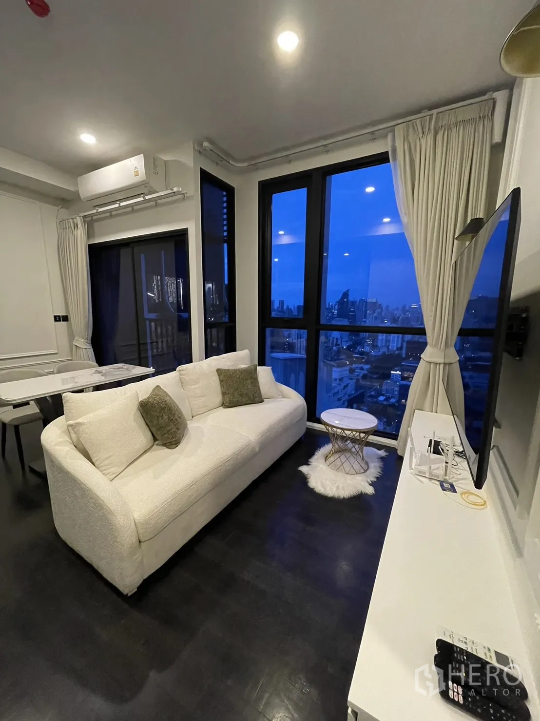 Condominium for rent in Watthana, Bangkok - Cozy sofa by floor-to-ceiling windows with panoramic skyline view.