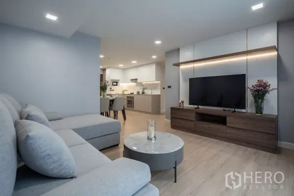 Apartment for rent - Open-plan living area with TV wall, wood media console, dining set and modern kitchen with soft LED lighting.