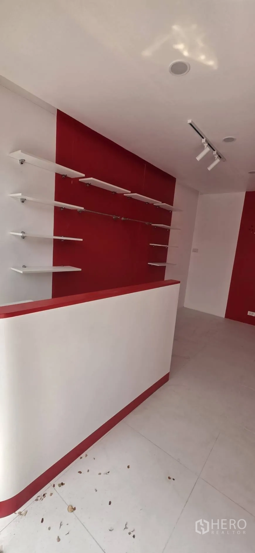 Retail Space for rent in Watthana, Bangkok - Interior angle showing a white counter with red accents and floating wall shelves.