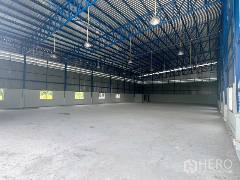 Warehouse for rent in Min Buri, Bangkok - Wide interior shot with smooth concrete floor, skylight panels, and multiple windows for natural light.