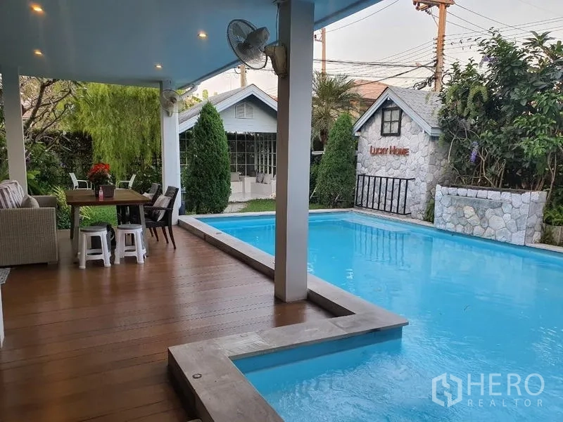 บ้าน ขายในLam Luk Ka, Pathum Thani - สระว่ายน้ำส่วนตัว พร้อมชานระเบียงมีหลังคา พัดลมเพดาน ผนังหิน และสวนสีเขียว.
