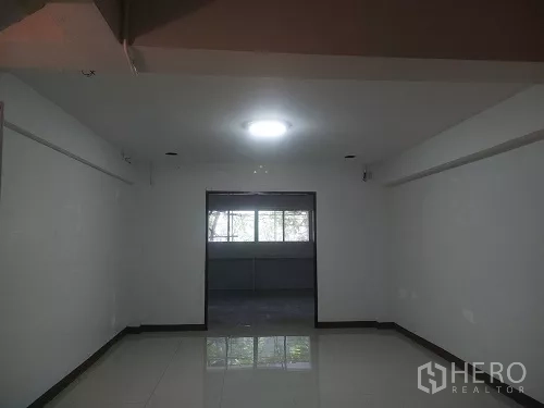 Shophouse for rent in Bang Rak, Bangkok - Long room with central ceiling light and rear windows.