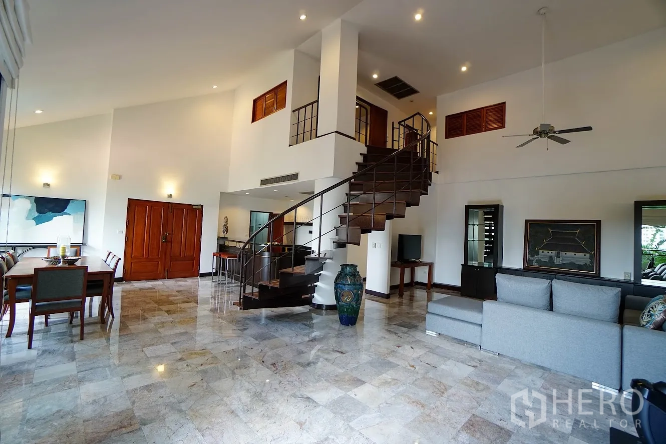 房间 出租在Watthana, Bangkok - 双层挑高客餐厅，吊扇与大弧形楼梯。